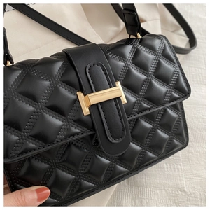 Close-up of black quilted shoulder bag featuring a gold H-shaped metal clasp and leather texture