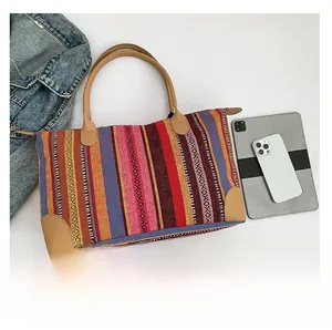 Detail of colorful woven tote bag featuring reinforced brown leather base and zip closure