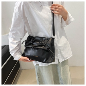 Detail of black matte leather tote bag with elegant bow accents and gold lettering