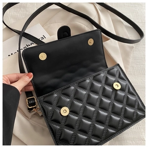 Detail of black quilted leather handbag with gold magnetic snaps and interior lining
