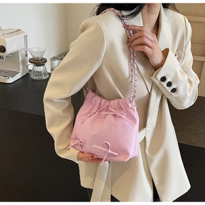 Gros plan détaillé du sac seau rose clair avec des nœuds en ruban et une bandoulière chaîne