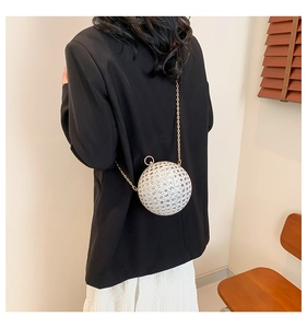 Chic round evening bag with gold chain and shimmering sequin details on a model