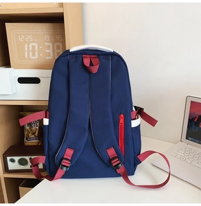 Detail of blue nylon backpack featuring red straps and white side pocket with buckle