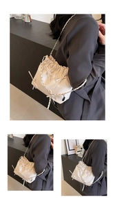 Détail du sac seau blanc avec nœuds décoratifs et bandoulière en chaîne argentée