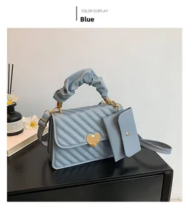 Detail view of light blue quilted handbag with gold heart clasp and stylish ruched handle