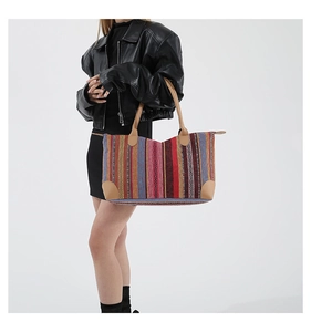 Detail of bohemian tote bag showing colorful vertical stripes and faux leather handle