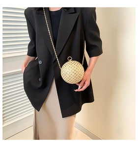 Detail of spherical hollow woven handbag with a golden metal chain on a model