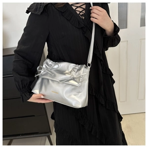 Close-up of silver tote bag with ruffled edges, chic ribbon bows and gold logo detail