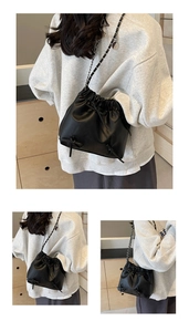 Détail d'un sac seau noir mat avec nœud papillon et bandoulière en chaîne sur mannequin