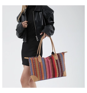 Detailed shot of large striped woven tote bag with brown leather handles on shoulder