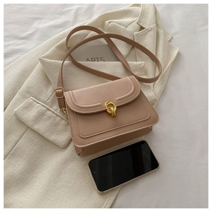 Detail of nude pink crossbody bag with gold double-ring clasp on beige suit jacket