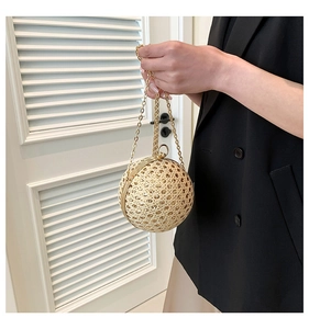 Detailed view of spherical woven evening bag with gold metal handle and chain strap