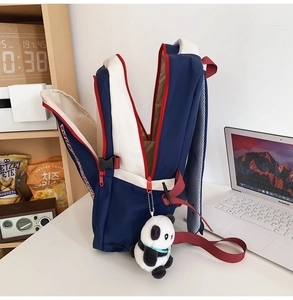 Detail of multi-compartment navy and white school backpack with cute panda charm