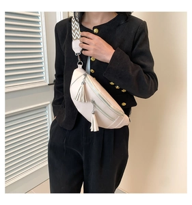 Détail d'un sac banane en cuir blanc cassé avec fermetures à franges et bandoulière