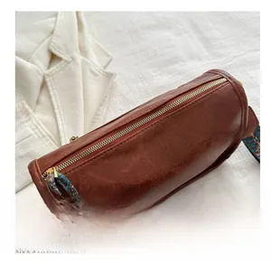 Détail du sac cylindrique marron avec texture cuir vintage et bandoulière colorée