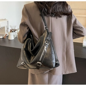 Détail du sac cabas en cuir noir avec zips argentés et boucles sur un sac bandoulière chic