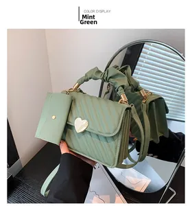 Detail of bean green crossbody bag with V-shaped quilting and golden heart buckle