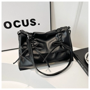 Close-up of black soft tote bag with decorative bows and stylish pleated texture
