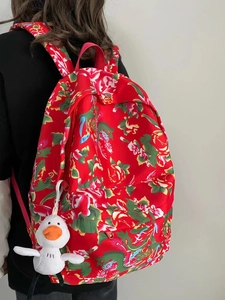 Detail view of ethnic red floral backpack with dragon patterns and plush duck charm
