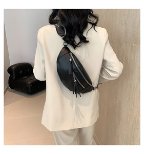 Détail du sac bandoulière en cuir noir avec pompons et large sangle tissée à motifs