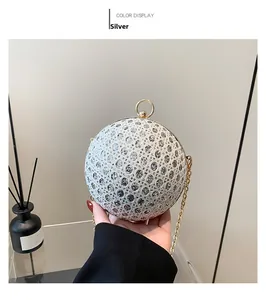 Detail of silver spherical evening bag with sparkling rhinestones and gold ring handle