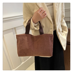 Detailopname van de bruine corduroy tote bag textuur en geweven handvatten