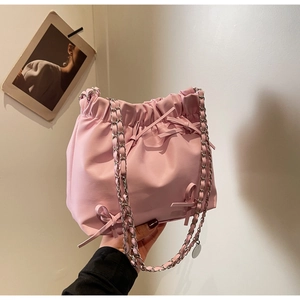 Détail du sac seau plissé rose clair avec nœud décoratif et bandoulière chaîne argentée