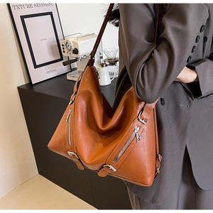 Gros plan du sac hobo en cuir marron caramel avec fermetures éclair argentées