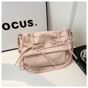 Detail of light pink tote bag featuring soft pleats, bow accents and gold brand logo