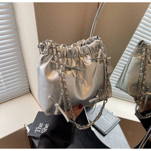 Détail du sac seau argenté métallisé avec nœuds décoratifs et bandoulière en chaîne