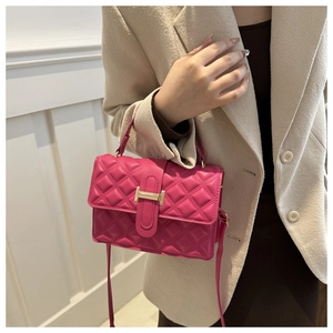 Detail of fuchsia quilted crossbody bag with gold H-buckle worn on beige blazer