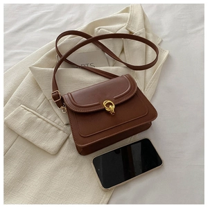Detail view of brown leather shoulder bag featuring a golden double-ring buckle and strap
