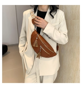 Détail d'un sac banane en cuir marron avec de longues franges et une bandoulière géo