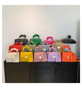 Detail of colorful quilted handbags with ruffled handles and heart-shaped metal locks