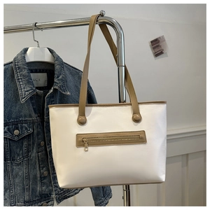 Dettaglio della borsa tote bianca con manici kaki e tasca frontale con zip dorata