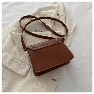 Detail of caramel brown faux leather shoulder bag featuring a gold metal clasp and fine texture