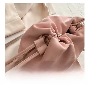 Close-up of pink drawstring bucket bag with gold chain strap and suede texture