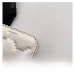 Close-up detail of white quilted faux leather texture and embossed double C logo on crossbody bag