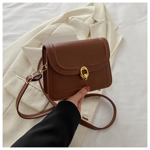 Detail of vintage brown leather crossbody bag with elegant gold interlocking buckles