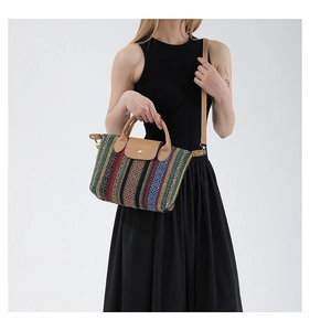 Detailed view of woven striped tote bag with leather straps and magnetic flap closure
