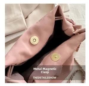 Detail view of the pale pink leather bucket bag showing dual gold magnetic snap closures