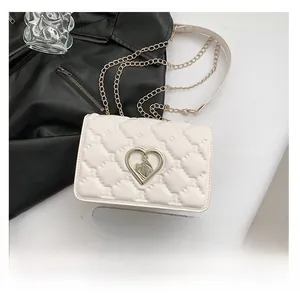 Macro detail of white quilted crossbody bag with heart lock and chain strap size comparison