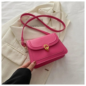 Detail view of pink leather crossbody bag with golden metal buckle on beige background