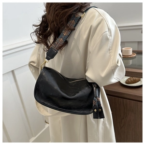 Détail du sac hobo noir avec une large bandoulière de style ethnique sur un mannequin