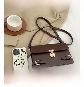 Detail view of brown vintage messenger bag showing golden rotary lock and buckled straps