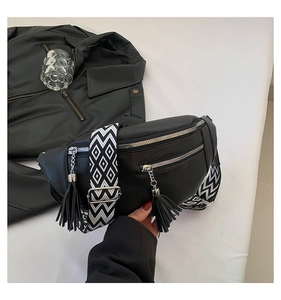 Détail du sac de poitrine en cuir noir avec pompon et bandoulière tissée géométrique