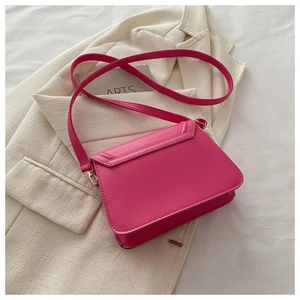 Close-up of fuchsia crossbody bag texture and golden metal hooks on beige background