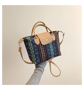 Detail showing ethnic style woven fabric and brown leather handle on a large tote bag