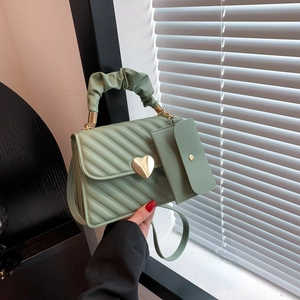 Mint green quilted crossbody bag with heart lock and pleated handle shown in soft sunlight