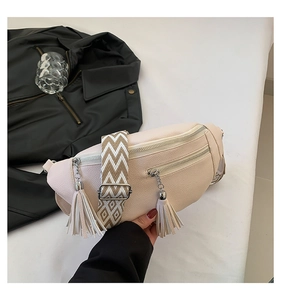 Détail du sac de poitrine en cuir beige avec glands et bandoulière tissée large